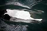 30.4.2007 Morteratschgletscher - Wolkensicht aus Eisspalte.<br />- Da wo der Fu der steilabfallenden Morne den Gletscher an seinem Ende trifft, zeigt sich die Eiswand hoch und unnahbar. Kein direktes Sonnenlicht erreicht diesen nach Norden gerichteten Ort!<br />- Die Wand hat sich hier im untersten Teil ein wenig geffnet, ein eingeknickter Deckenbogen ermglicht ein Unterqueren. Was aufgetaut und vom Eis befreit, findet den Weg zu den Kanten der Brckenunterseite und entldt sich dort als tropfende Pforte! Dahinter sieht man sich alsbald am Grund dieser Eisspalte. Das grelle Auen direkt aus der Senkrechten zwingt die auftauenden, lchrigen Flchen zu einem Widerschein zwischen Grau und dunklem Blau. Steine oben auf der Auftaukante mahnen zur Vorsicht.